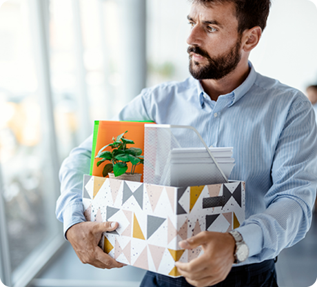 Professional in business attire carrying a box with personal belongings after job loss